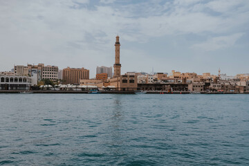 Fototapeta na wymiar View of Dubai Creek channel with traditional Abra boats and piers. Famous tourist destination in UAE, United Arab Emirates. Historic Old arab town. Deira Old Souk. Artificial river length of 3 km