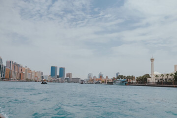 Naklejka premium View of Dubai Creek channel with traditional Abra boats and piers. Famous tourist destination in UAE, United Arab Emirates. Historic Old arab town. Deira Old Souk. Artificial river length of 3 km