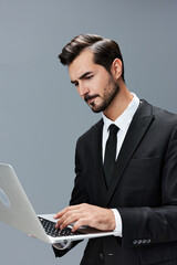 Man business looks into laptop and works thoughtfully online via internet in business suit video call business talks on gray background copy place