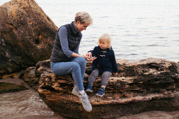 Mother and son have a fun near the sea in autumn time