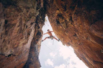 Mountain or rock climbing, cliff hanging and adrenaline junkie with courage on adventure trying to balance between gap. Athletic climber man doing fitness, exercise and workout during extreme sport © David L/peopleimages.com