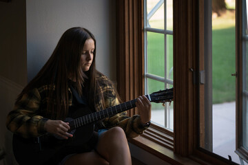 female songwriter, musician playing the guitar.