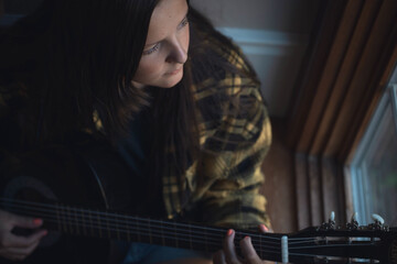 female songwriter, musician playing the guitar.