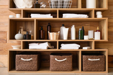 Obraz na płótnie Canvas Different bath accessories on shelf unit near wooden wall, closeup