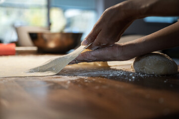 Low angle view of a woman stretching and pulling homemade vegan pastry dough