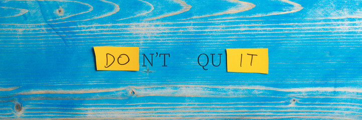 Wide view image of a Dont quit, Do it sign spelled on yellow papers