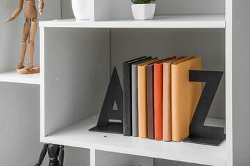 Obraz na płótnie Canvas Bookcase with stylish holder near light wall