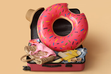 Open suitcase with different beach accessories on color background