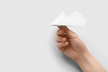 Woman with white paper plane on light background