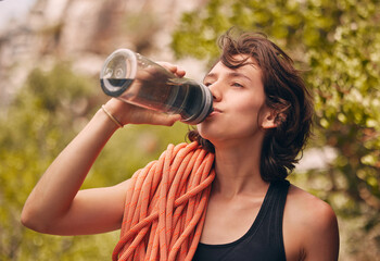 Water bottle, hiking and exercise with woman feeling thirsty and staying hydrated during fitness workout or rock climbing in nature. Health, wellness and electrolyte with athlete female on adventure