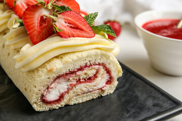 Board with delicious strawberry roll cake on table, closeup