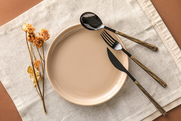 Table setting with dry roses on brown background - obrazy, fototapety, plakaty