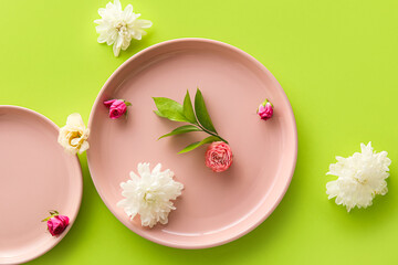 Obraz na płótnie Canvas Plates and beautiful flowers on green background