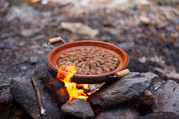 Moroccan Tajines cooked on wood fire; cooking in traditional moroccan tajine pot over open fire; tajine of meatballs