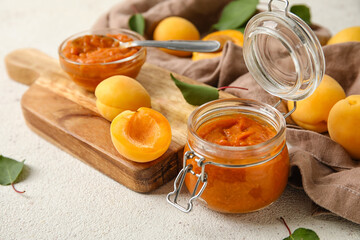 Jar of sweet apricot jam on light table, closeup