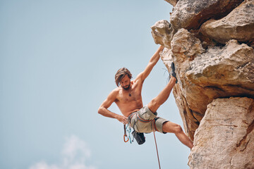Mountain or rock climbing, cliff hanging and adrenaline junkie out on adventure and checking his...