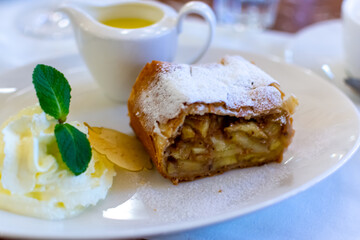 Austrian sweet dessert, portion of apple strudel with whippen cream and hot vanilla sauce served in old bakery cafe in Vienna, Austria