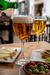 Lunch with cold beer in Spanish outdoor cafe, tapas bowl with green olives and Spanish cheese manchego with nuts
