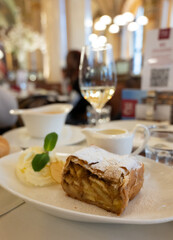 Austrian sweet dessert, portion of apple strudel with whippen cream and hot vanilla sauce served in old bakery cafe in Vienna, Austria