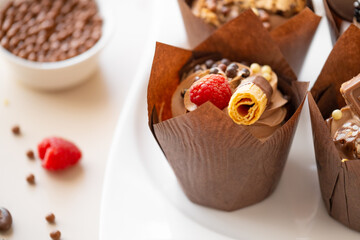  cupcake with raspberries and crispy waffles,chocolate decor on a beige background.Chocolate dessert.Chocolate cupcake.Appetizing muffin set.Assorted sweet table.Baked goods and desserts 