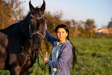 Foto op Canvas  beautiful black horse  with his owner and rider  posing in green grass meadow. spring time © anakondasp
