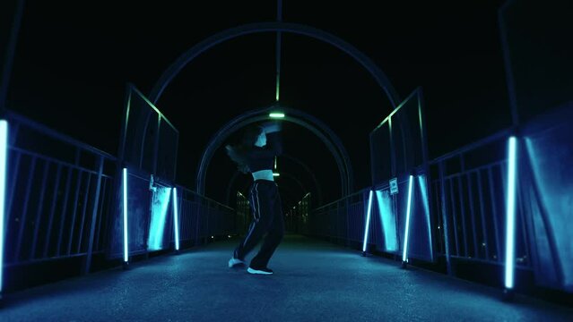 beautiful young woman is dancing alone in dark metro corridor, passion and energy of talanted dancer