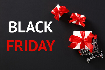 Black Friday sale banner. Shopping cart with gifts inside and message BLACK FRIDAY on black background.