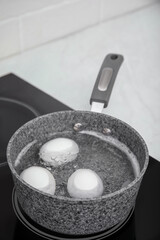 Boiling chicken eggs in saucepan on electric stove
