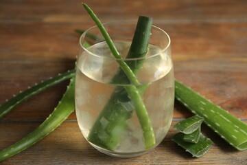 Fresh aloe drink with leaves in glass on wooden table, closeup