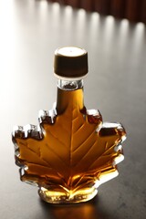 Leaf shaped bottle of tasty maple syrup on light grey table