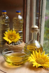 Organic sunflower oil and flower on wooden table, closeup