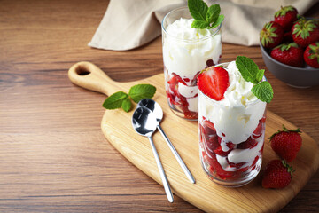 Delicious strawberries with whipped cream served on wooden table. Space for text