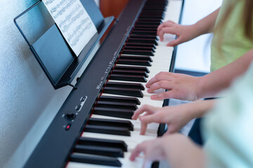 Midi keyboard or electronic piano and children's hands playing. Music education for a child in a...