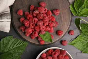 Fresh ripe raspberries with green leaves on black table, flat lay