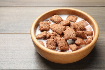 Tasty corn pads with milk in bowl on wooden table, closeup