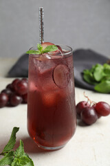 Delicious grape soda water with mint on white table. Refreshing drink