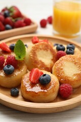 Delicious cottage cheese pancakes with fresh berries and honey on white wooden table, closeup
