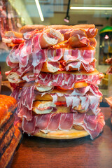 Spanish street food, fresh baked baguette bread with sliced iberian cured ham jamon, bocadillo