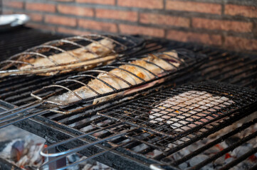 Fresh fish grilling on old charcoal parrillas build outside of buildings in small fisherman's...