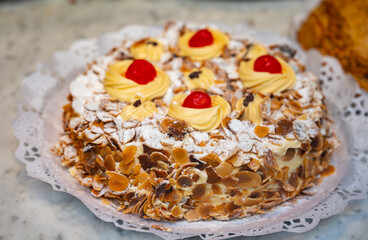 Cake with cream and roasted almond nuts on display in artisanal bakery in San Sebastian city,...