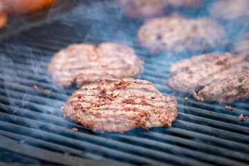 Grilling meat cutlets for burgers. Fast food or street food. Steel grill grate, cutlet in the smoke. Selected focus, close-up