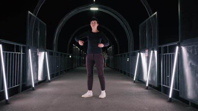 woman is dancing like robot in dark tunnel in night city, flashmob of modern street dancers in urbanscapes