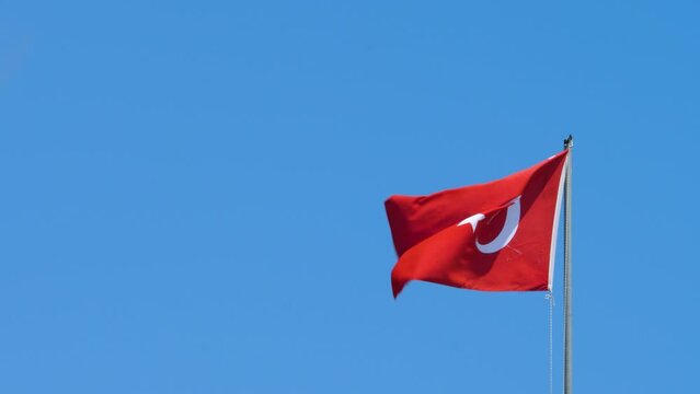 Flag of Turkey swings in wind. Country straddling Western Asia and Southeast Europe. Wind blows on blue sly no cloud background