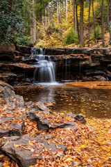 Fototapeta na wymiar Peaceful scenery of silky waters cascading in this small falls amidst the autumn forest in Swallow Falls state park in Maryland.