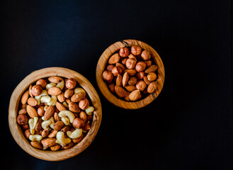 Nuts in assortment in a wooden bowl with a place to copy.