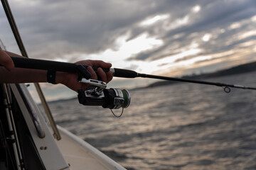 Fishing rod wheel closeup, man fishing with a beautiful sunrise behind him