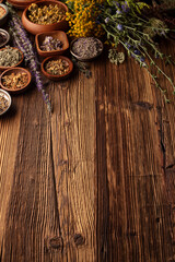 Fototapeta na wymiar Natural medicine background. Assorted dry herbs in bowls, mortar and plants on rustic wooden table.