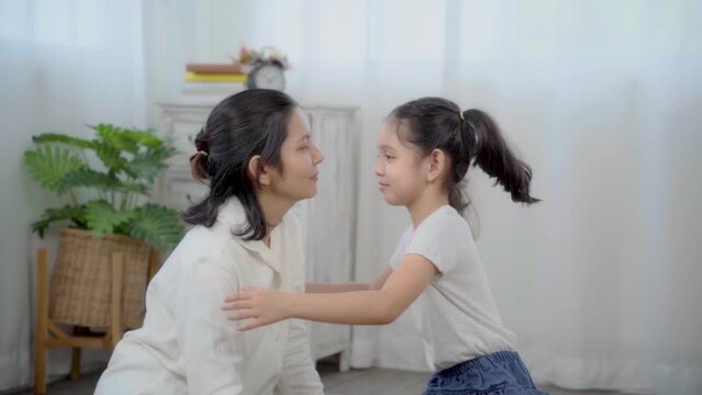 Beautiful Asian mother play with adorable girl at home, happy kid kiss mom with love and tender, happiness motherhood, family activities, mom and daughter get together with fun and joyful, slow motion