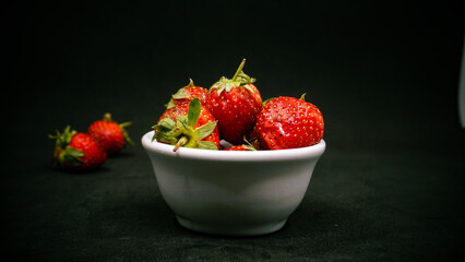 Fresh ripe delicious strawberries in a white bowl on a black background