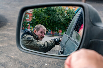 A street thief opens the back door of a car from a careless driver. View in the rear view mirror